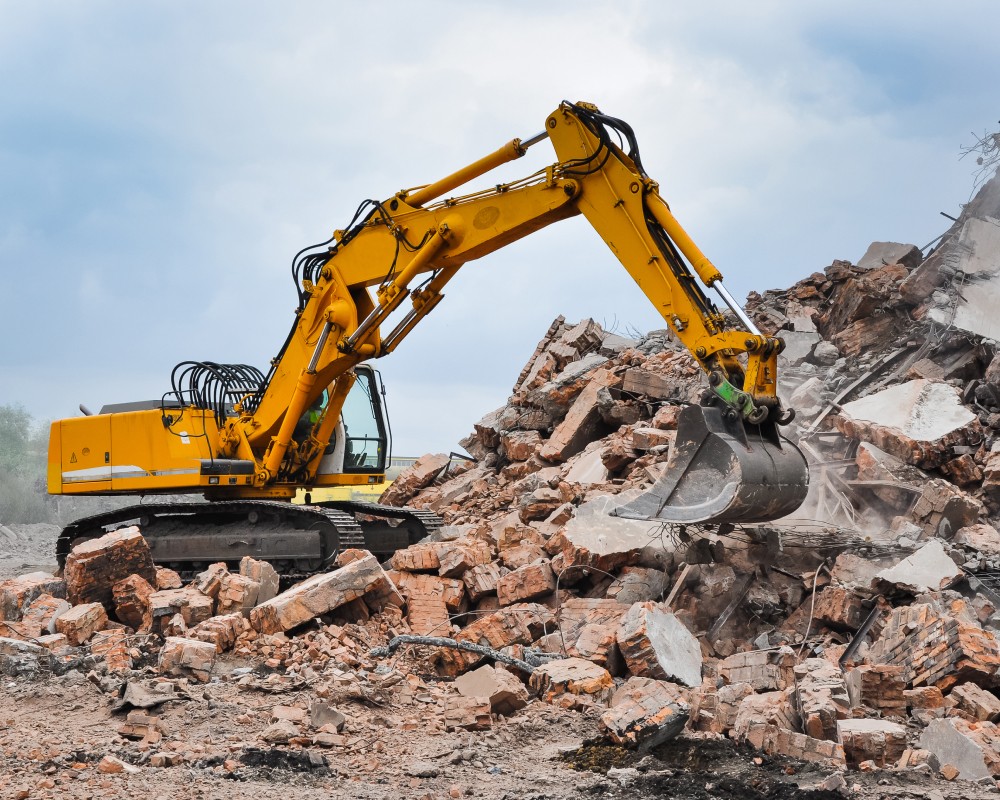 Yellow excavator being used to demolish building Missoula MT